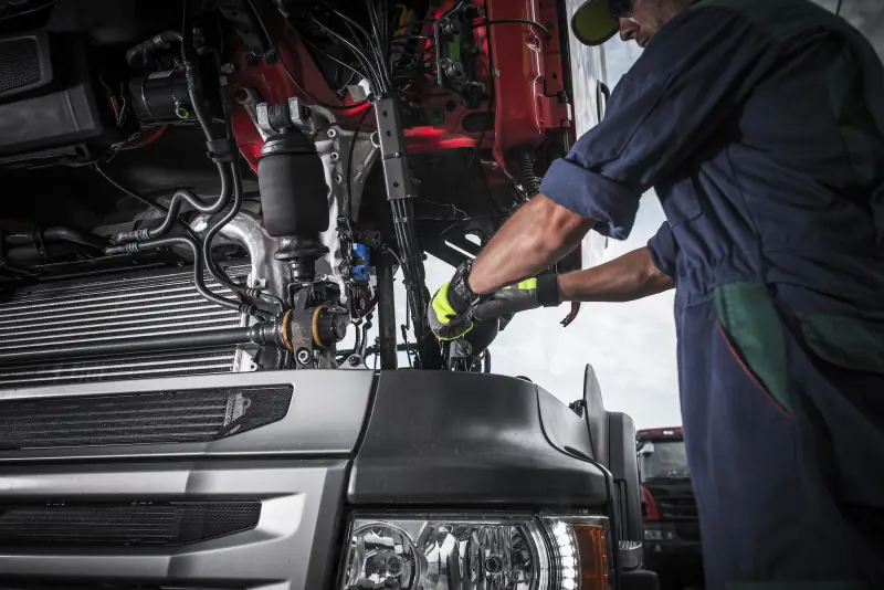 Illustration: mechanic in gloves working on the engine of a truck with its cab tilted