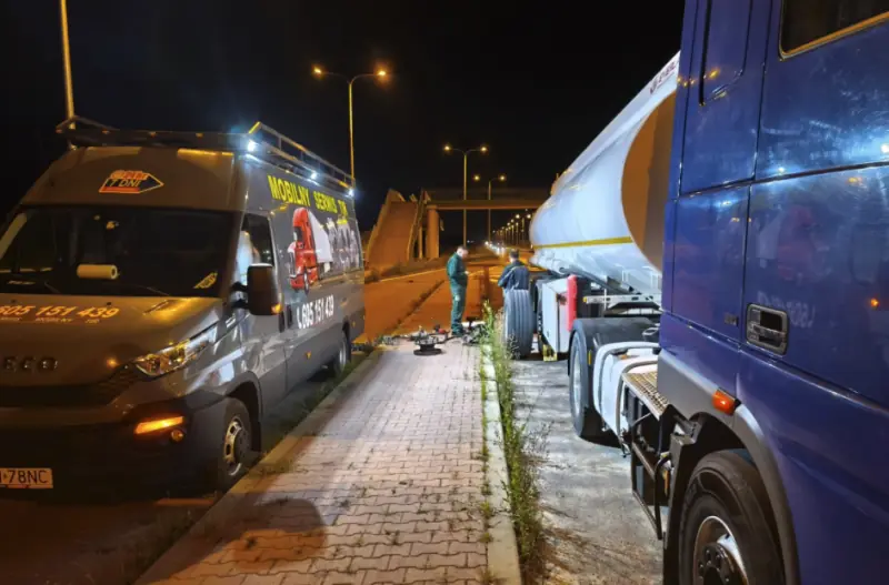 Mechanicy naprawiają koło cysterny nocą przy drodze, obok stoi bus Mobilnego Serwisu TIR