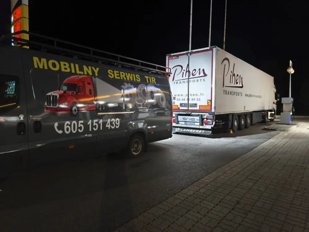 Mobile truck service van at night next to a semi-trailer at a petrol station