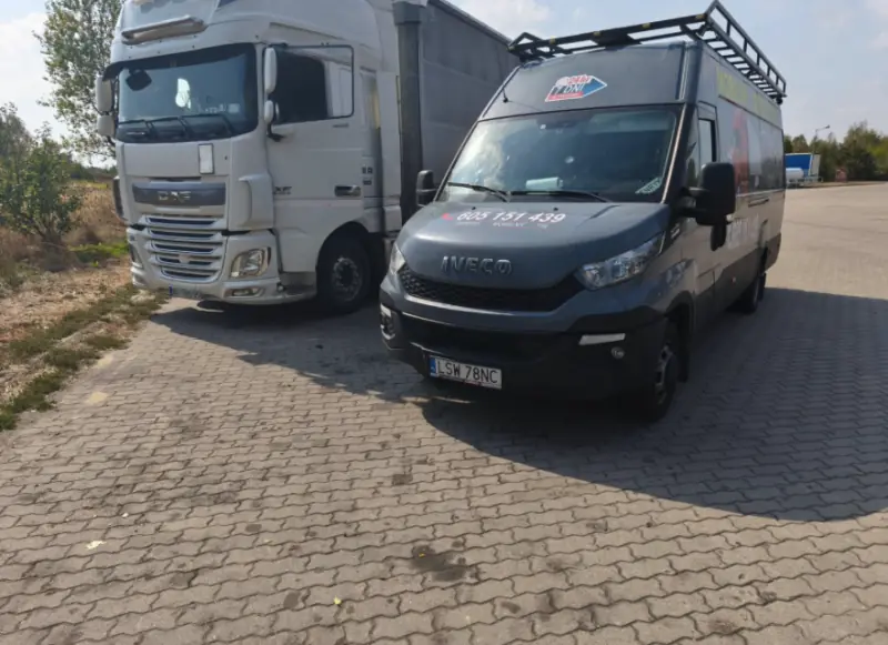 Bus Mobilnego Serwisu TIR obok białego ciągnika DAF XF na wybrukowanym parkingu