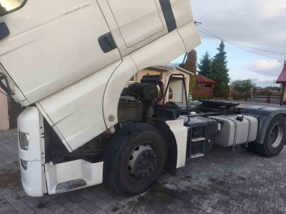 MAN TGX 18.480 tractor unit with its cab tilted for a repair on a block-paved yard