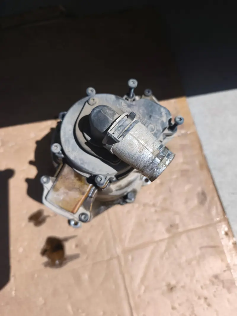 Removed component with a hose connector lying on cardboard next to an oil stain