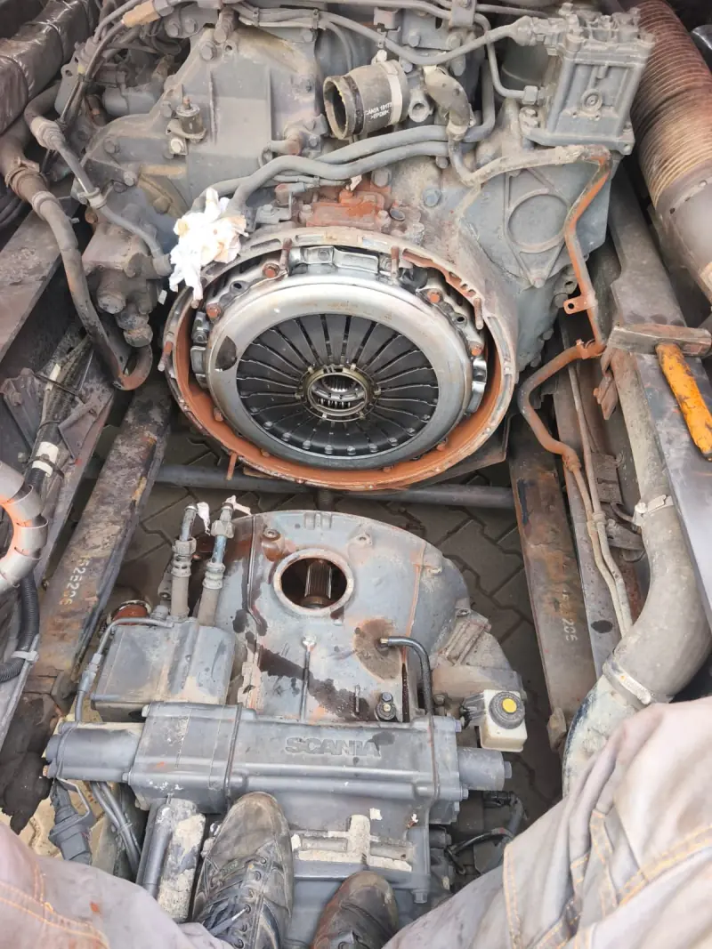 Exposed clutch pressure plate on the engine and a removed Scania gearbox below the truck