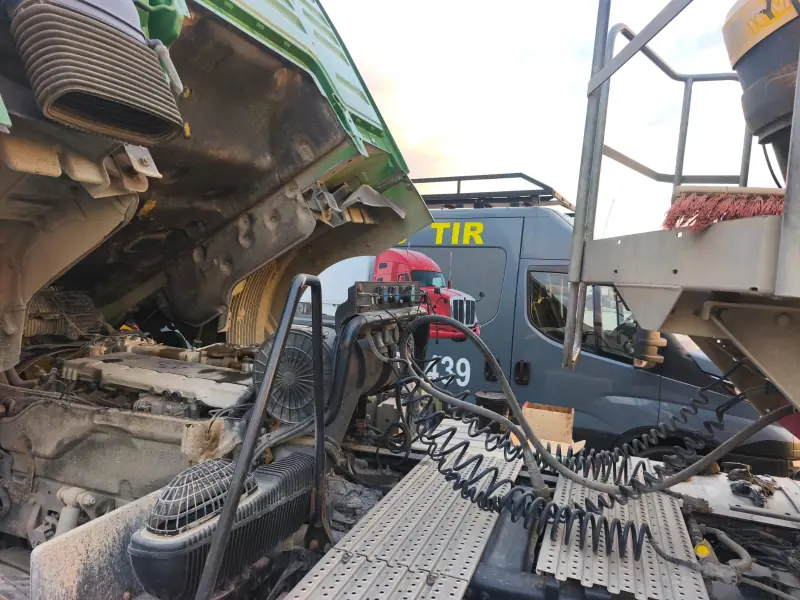 Tilted cab exposing the truck engine, with the mobile service van in the background
