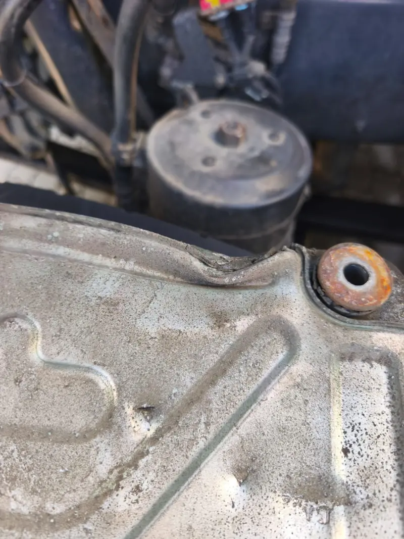 Bent and cracked corner of the aluminium ECU housing at a mounting hole
