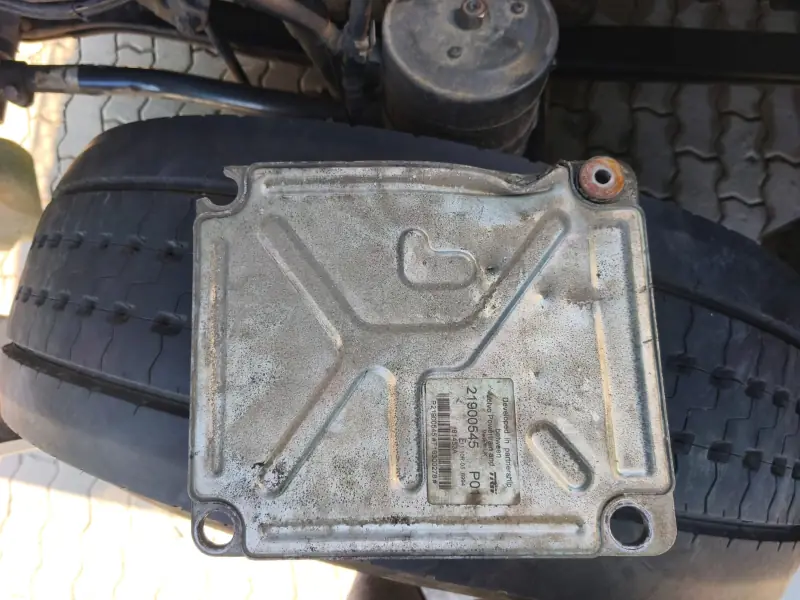 Underside of the removed ECU with its rating label, resting on a tyre